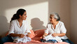© Anna - Young woman helping her elderly mother fold laundry at home. Daughter and senior parent talking and bonding while doing household chores. Intergenerational care and family relationship concept