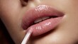 © Oleh - Woman applying shiny pink lip gloss with an applicator, enhancing her plump lips with a glamorous and lustrous finish, symbolizing beauty, makeup, and cosmetic care