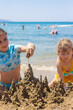 © yanadjan - Children playing with sand on the beach. Selective focus.