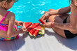 © yanadjan - Children eat watermelon near the pool. selective focus.