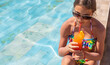 © yanadjan - Woman in the pool with a cocktail. Selective focus.
