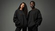 © Lubov - Black male and female models wear matching stylish black sweatshirts. They stand together confidently showing off sleek casual wear. Duo looks trendy and modern.