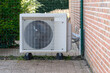 © Anna Kondratiuk - Outdoor unit of a modern air source heat pump installed next to a brick wall of a residential house. Energy-efficient heating system and renewable energy technology for sustainable home climate