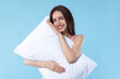 © New Africa - Beautiful woman with pillow on light blue background