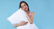 © New Africa - Beautiful woman with pillow on light blue background. Space for text