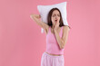 © New Africa - Woman with pillow yawning on pink background