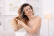 © New Africa - Unhappy woman trying to brush her tangled hair at home