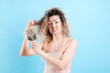 © New Africa - Unhappy woman trying to brush her tangled hair on light blue background