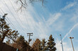 © DSMT - Clouds fill the sky over a city with trees, power lines, and street lights during the day in early spring