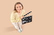© Pixel-Shot - Beautiful actress with movie clapper on beige background