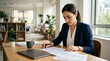© sumi yati - Focused businesswoman working on documents at her desk in a modern office