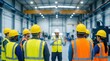 © Pinit - Team of industrial workers, equipped with hardhats and high-visibility vests, receive instructions on job hazard analysis from a safety auditor in a warehouse.
