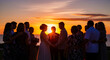 © Visual Verse - Romantic wedding couple silhouette at golden sunset beach with guests celebrating