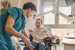 © PintoArt - Healthcare worker helping smiling woman in electric wheelchair
