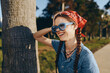 © SHOTPRIME STUDIO - smiling woman with braids wearing sunglasses and red bandana outdoors in warm sunlight enjoying nature and casual blue denim shirt