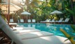 © ahmadadi - Vibrant blue pool lined with white sunbeds amidst lush tropical greenery and bright sun
