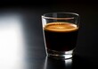 © monirs33 - A glass of espresso on a dark surface with a light shining on it