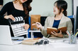© Nuttapong punna - Creative team planning video production in modern office, using clapperboard, laptop and notebook. Business, marketing, content creation