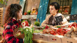 © DC Studio - Female stall holder selling natural fruits and vegetables outside at farmers market stand, presenting bio food. Young vendor giving organic eco fresh products to vegetarian client.