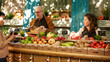 © DC Studio - Vegetarian couple shopping at local farmers market on sunny day. Young man and woman standing at local produce counter looking at various locally grown organic fruits and vegetables.