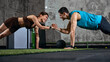 © master1305 - Man and woman doing partner plank exercise high five in gym training session. Concept of teamwork, motivation, partner workout and strength training discipline