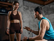 © master1305 - Man holding stopwatch giving instructions to woman during strength training session. Concept of guided workout, personal coaching service, fitness onboarding and technique improvement