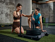 © master1305 - Woman pushing weighted sled with man supervising gym strength training. Concept of fitness advertising, gym promotion campaign, strength program branding and personal training service