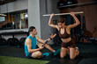 © master1305 - Woman lifting stick overhead while man evaluates form in gym training. Concept of fitness advertising, mobility program promotion, wellness branding and professional coaching service marketing