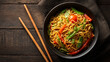 © Sabana - A black bowl overflows with savory noodles and colorful vegetables, ready to eat.
