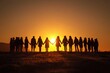 © Olena - Silhouetted diverse group joining hands in unity against a sunset sky