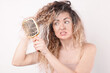 © New Africa - Unhappy woman trying to brush her tangled hair on light grey background