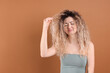 © New Africa - Unhappy woman with tangled damaged hair on brown background, space for text