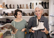© JackF - Happy elderly woman and adult woman shoppers buyer chooses boots in shoe store