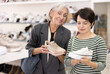 © JackF - Elderly and adult female customers purchases pair of sneakers in shoe store