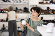 © JackF - Adult woman buyer chooses pair of sneakers in shoe store