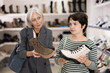© JackF - Two women are shopping in shoe store and young colleague shows elderly lady advantages of thick sole in modern winter boots
