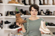 © JackF - Adult woman buyer chooses pair of boots in shoe store