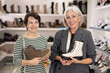 © JackF - In shoe store, young woman admires cool design of trendy model of winter brown mid-calf boots and shows them to elderly mother