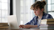 © Visual Studio - Teenager Focused on Digital Learning at Home: Technology and Homework in a Modern Workspace with Laptop and Books