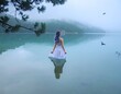 © Messer Meckie  - 霧に包まれた静かな湖畔の崖に立ち遠くを見つめる白いドレスを着た紫色の髪の女性と飛翔する白い鳥の風景