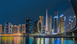 © Mina - Modern buildings in the city center of Dubai in the evening. Illuminated skyscrapers in the financial center at the blue hour. View of skyline in united arab emirates at night and reflection