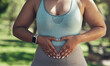 © peopleimages.com - Health, heart hands and stomach with woman outdoor for exercise, fitness or training routine. Abdomen, diet and gut with person in park for commitment or dedication to weightloss and wellness