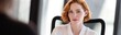 © Andrii Zastrozhnov - Red haired woman posing thoughtfully at office desk