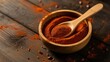 © Ghulam - Red paprika powder sitting inside a small wooden bowl with a matching bamboo spoon resting on a rustic dark surface