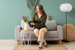 © Pixel-Shot - Young woman with tulips sitting on sofa in living room