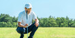 © buritora - A male golfer reading the line on the green of a golf course.