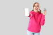 © Pixel-Shot - Happy young woman with money and blank mobile phone on light background. Sports bet concept
