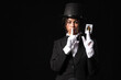 © Pixel-Shot - Young African-American magician with card showing silence gesture on black background