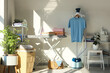 © Pixel-Shot - Interior of laundry room with clothes, shelf units and ironing board