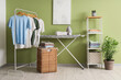 © Pixel-Shot - Interior of laundry room with clothes, shelf unit and ironing board